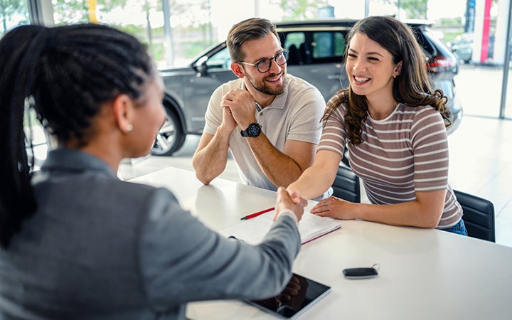 A couple talking to a Gross Auto salesperson at the table