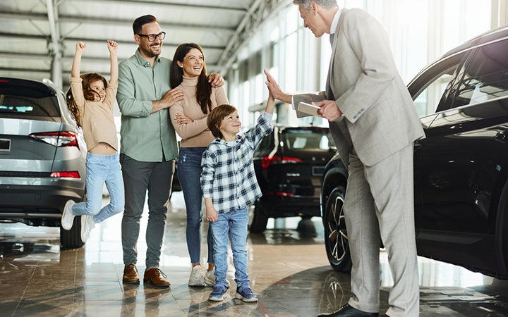 A happy family talking to a Gross Auto Group sales person